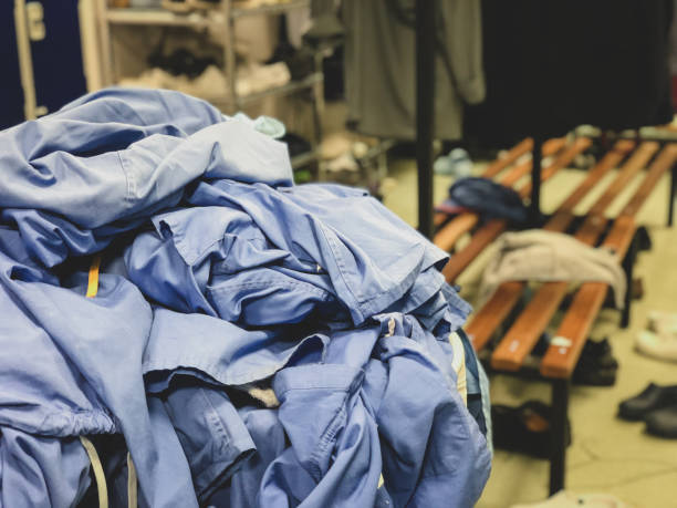 una cesta de ropa rebosante de exfoliantes quirúrgicos en el vestuario de un hospital en el reino unido-ambiente desordenado del vestuario. - shirt hanger hanging blue fotografías e imágenes de stock