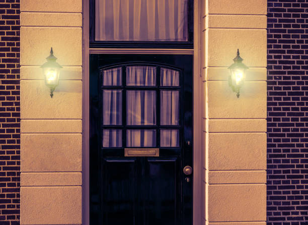 istock wooden front door with lighted wall lanterns shining light in the dark, Dutch architecture by night 1132540623
