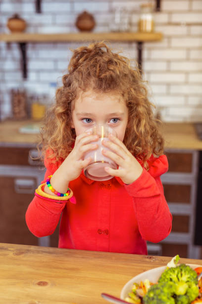 istock Concentrated blonde girl drinking yoghurt after dinner 1132541227