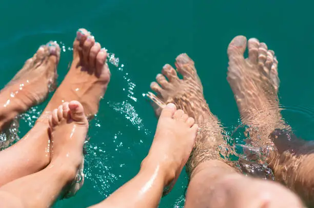 Photo of Happy family. Bare feets in the water of the sea boy, mother, father. Positive human emotions, feelings, joy. Funny cute child making vacations and enjoying summer.