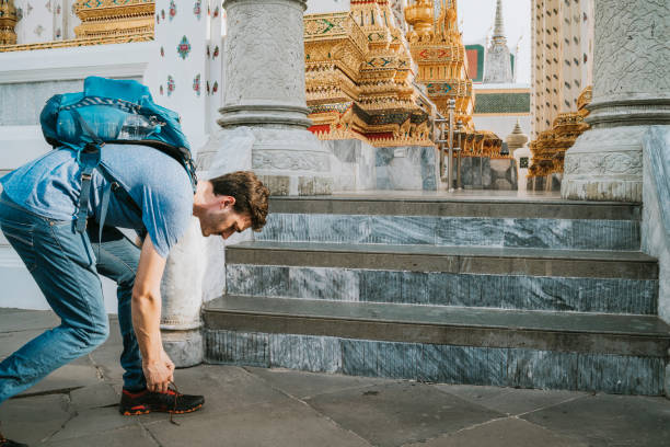 Young man taking off his shoes before entering a temple