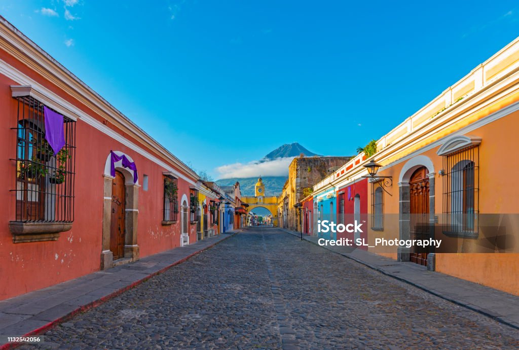 Antigua Cityscape at Sunrise, Guatemala Cityscape of the colorful main street of Antigua city at sunrise with the famous yellow arch and the Agua volcano in the background, Guatemala, Central America. Guatemala Stock Photo