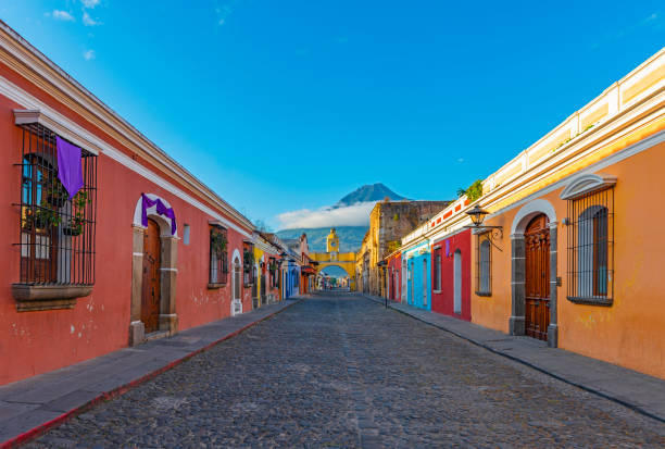 Antigua Cityscape at Sunrise, Guatemala Cityscape of the colorful main street of Antigua city at sunrise with the famous yellow arch and the Agua volcano in the background, Guatemala, Central America. guatemala landscape stock pictures, royalty-free photos & images