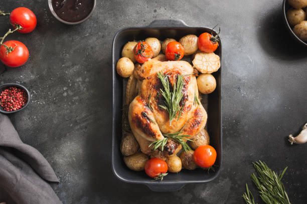 istock Roasted chicken with potatoes, tomatoes on black table. View from above. 1132543161