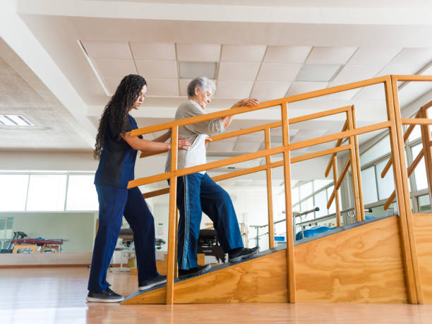 Senior woman going up a ramp during physical therapist - fotografia de stock