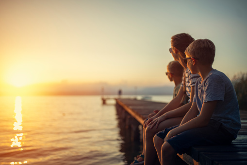 Three kids enjoying sunset at Garda Lake. Kids are sitting on a lake pier.
Nikon D850