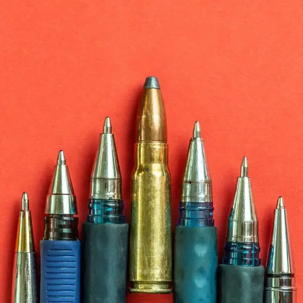 Photo of Bullet and pens on red background. Freedom of the press is at risk concept. World press freedom day concept