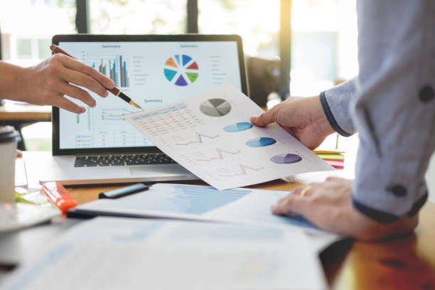 istock Midsection Of Business People Working Over Graph With Laptop On Table 1132548374