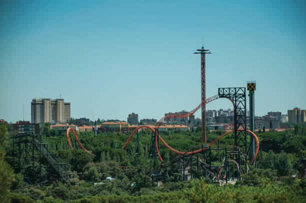 Roller coaster in amusement park on the horizon with trees in a sunny day, seen from the Teleferico Park of Madrid. Capital of Spain this charming metropolis has vibrant and intense cultural life.