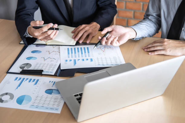 istock Midsection Of Coworkers Discussing Graphs On Desk In Office 1132557117