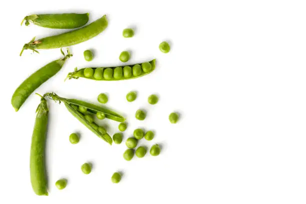 Photo of Green peas in pods and scattered on a white. The view from the top.