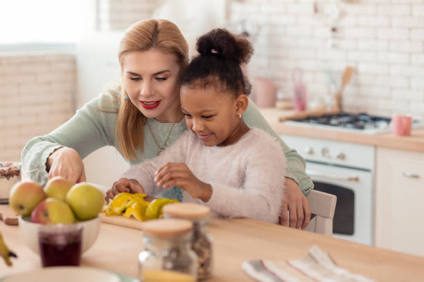 istock Cute curly girl feeling involved while helping her mother cooking 1132579435