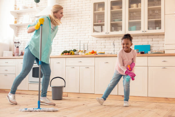 istock Cheerful foster daughter laughing while cleaning kitchen with mom 1132579513