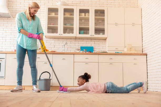 istock Mother having fun with daughter while mopping the floor 1132579564