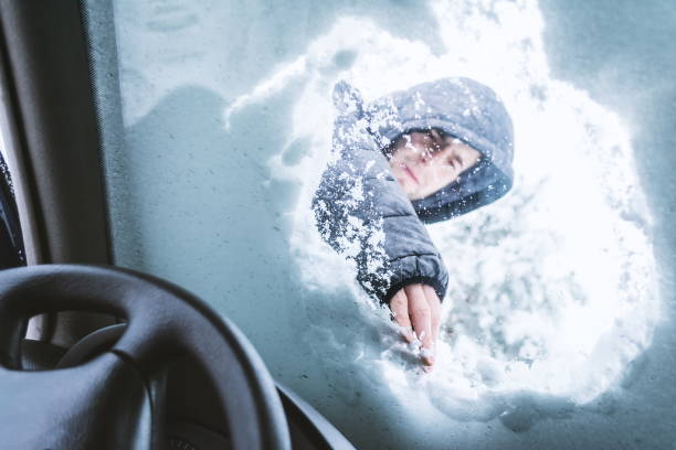istock Low Angle View Of Young Man Removing Snow On Windshield Seen Through Car 1132585281