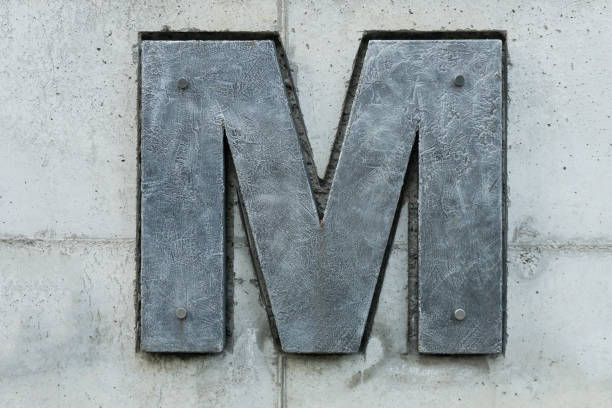istock dark gray letter m on light concrete back 1132588135