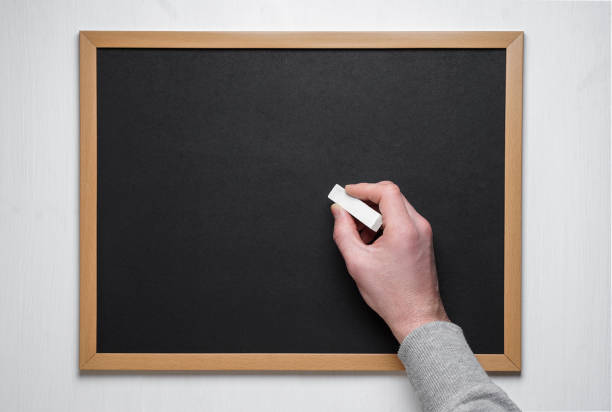 istock Male hand with chalk on the empty blackboard or chalkboard. 1132588260