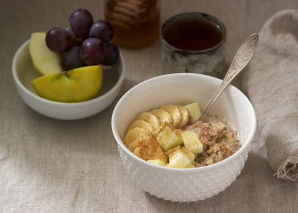 istock Buckwheat porridge with fruit, green tea, fruit and honey on a linen tablecloth. Rustic style. 1132588562