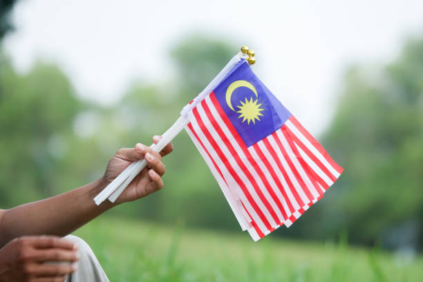 istock Cropped Hands Holding Malaysian Flags Against Trees 1132594482