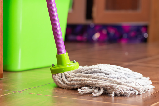 Rope mop for cleaning the floor on the background of a plastic bucket. Close-up, selective focus, green plastic bucket