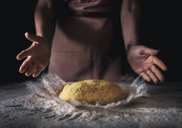 Chef dropping dough and flying flour on wooden table background
