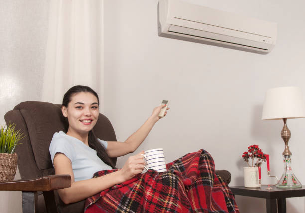 istock beautiful woman using remote control of air conditioner 1132598110
