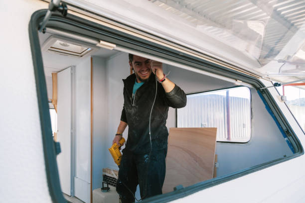 istock Young smiling man with a drill restoring his old caravan 1132599168