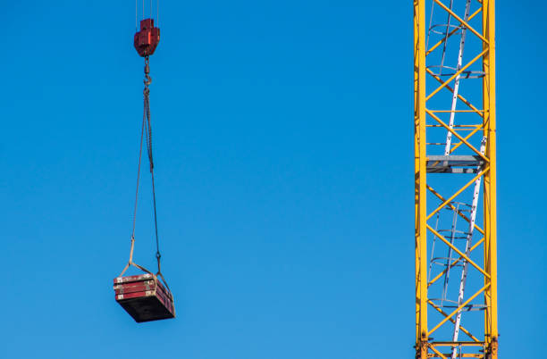 Crane lifting the nacelle to install it onto the tower of a wind turbine on a construction site, electricity, renewable energy and power concept, blue sky, copy space