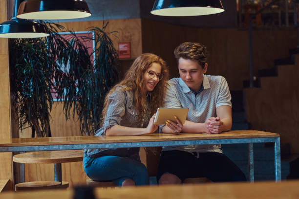 istock Thoughtful young couple students using a digital tablet while sitting at table in the college canteen during a break. 1132615317