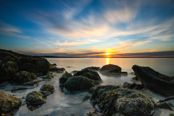 istock The sun setting on the horizon along a rugged coastline. 1132616834