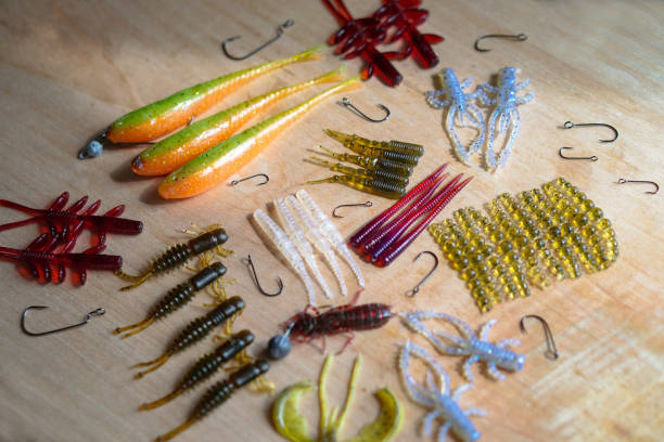 Colorful silicone fishing baits with plummets on wooden table. Various fish and worms and crayfish. Toned image and top view. Stock background, photo stock photo