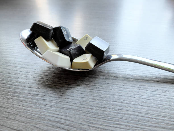 Black and white computer keyboard keys on the spoon to feed the computer model. Concept of unstructured big data that need to be sorted ready to be consumed by machine learning model for deep learning. stock photo