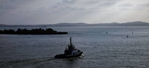 A tugboat moves across the bay with a portion of Manzanillo Island in the background