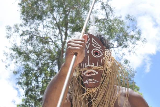 Queensland, Australia - January 11, 2019: Unrecognizable Torres Strait Islander man wears a traditional mask and dances a traditional Aboriginal dance for tourists in Torres Strait Islands near Australia's Cape York Peninsula and the island of New Guinea.