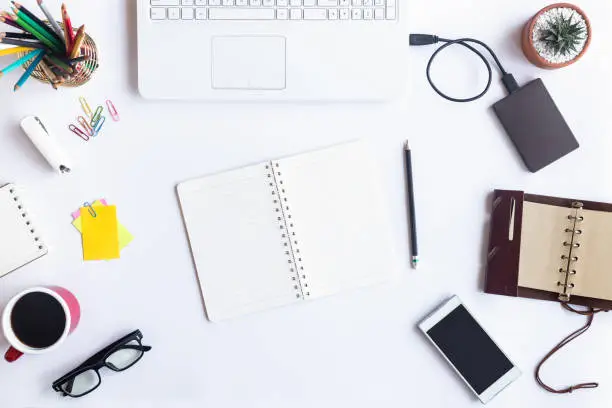 Photo of White desk office with laptop, smartphone and other supplies with cup of coffee. Top view with copy space for input the text. Designer workspace on desk top, view with essential elements on flat lay.