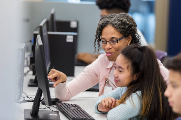 lehrer hilft schülern im computerlabor - science education child classroom stock-fotos und bilder