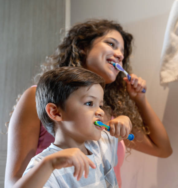 mother and son at home brushing their teeth - human teeth child smiling family imagens e fotografias de stock