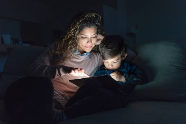 istock Mother and son watching videos on a tablet computer at nighttime 1132647583