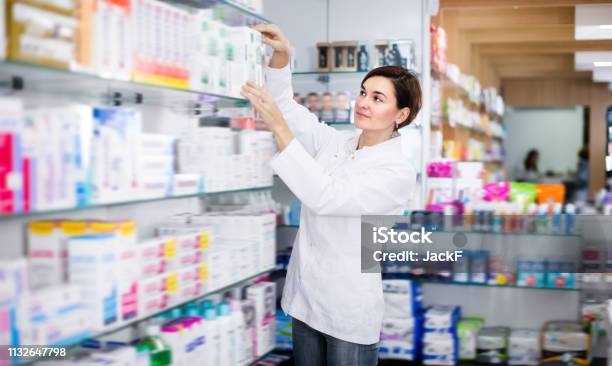 Pretty Female Pharmacist Offering Products Stock Photo - Download Image Now - Pharmacy, Pharmacist, Medicine
