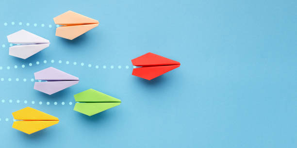 Red paper plane leading another ones, leadership concept Opinion leadership concept. Red paper plane leading another colorful ones, influencing the crowd, blue background, panorama persuasion photos stock pictures, royalty-free photos & images