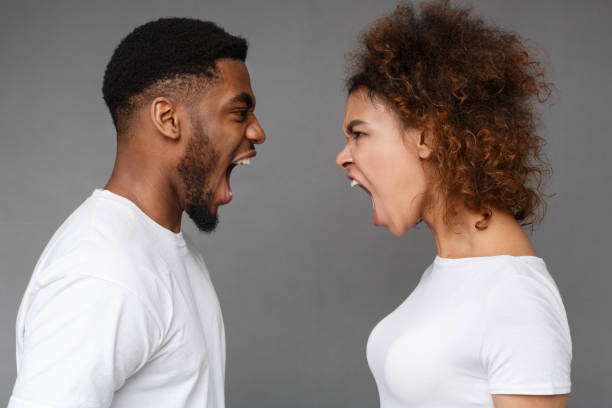 Young couple yelling at each other in studio Relationship crisis. Young african-american couple yelling at each other on gray studio background dueling stock pictures, royalty-free photos & images