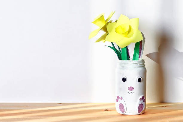 istock DIY Easter vase bunny with narcissus, daffodils from glass jar, felt, eyes on white wall background 1132649240