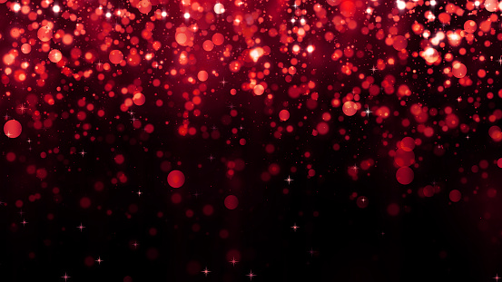 Holiday abstract red background with falling glitter particles. Beautiful festive sparkling luxury background. Shiny particle bokeh with magic light. Valentines day