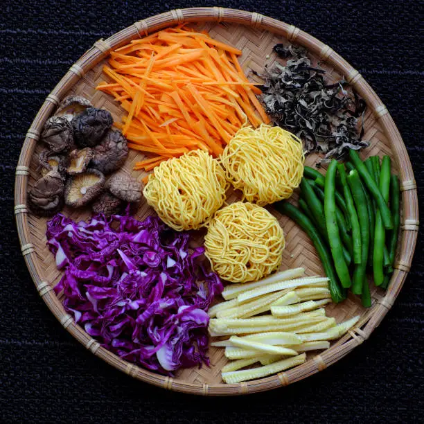 Raw materials for fry noodles mixed vegetables from top view, a Vietnamese vegetarian dish for vegans, with colorful greens, vermicelli and mushrooms, quick to  make for breakfast at home