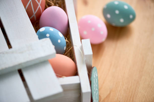 istock Close-up of open wooden box with painted eggs in hay on dining table 1132671521