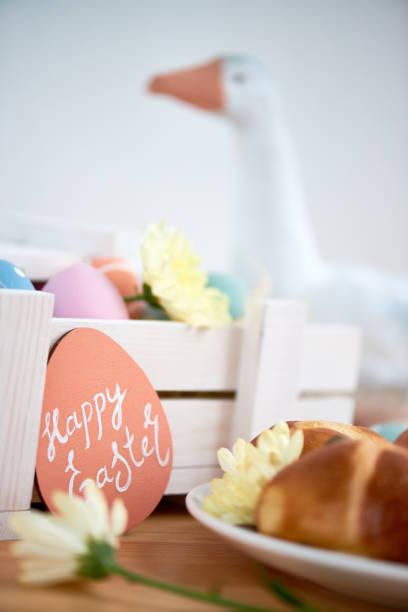 istock Easter table: focus on Easter card with wish leaning on wooden box full of eggs 1132671532