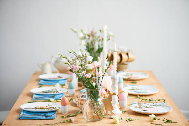 istock Flowers in vase and candles in candlesticks placed on decorated Easter table with tender flowers and colorful eggs in cups 1132671580