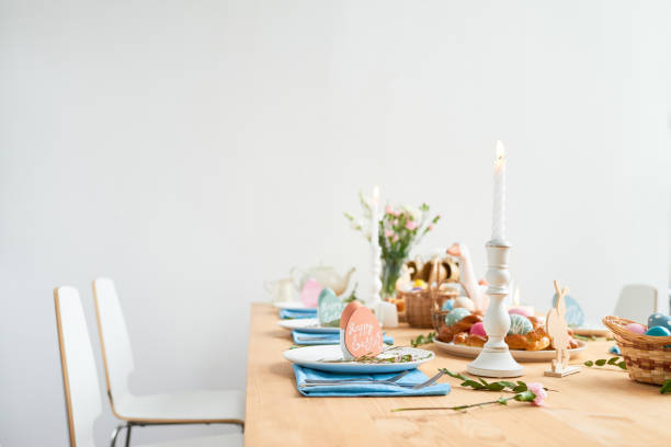 istock Burning candle in candlestick, flowers, happy Easter cards served on Easter table in dining room 1132671589
