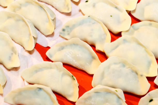 In Chinese families, the family prepares dumplings together, and mixes meat, onions, ginger, garlic, leeks, cabbage, and eggs to make dumplings and make Chinese dumplings. In Chinese families, the family prepares dumplings together, and mixes meat, onions, ginger, garlic, leeks, cabbage, and eggs to make dumplings and make Chinese dumplings. 塞滿的 stock pictures, royalty-free photos & images