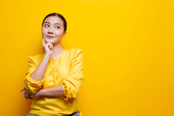istock Happy woman thinking and standing isolated over yellow background 1132674551